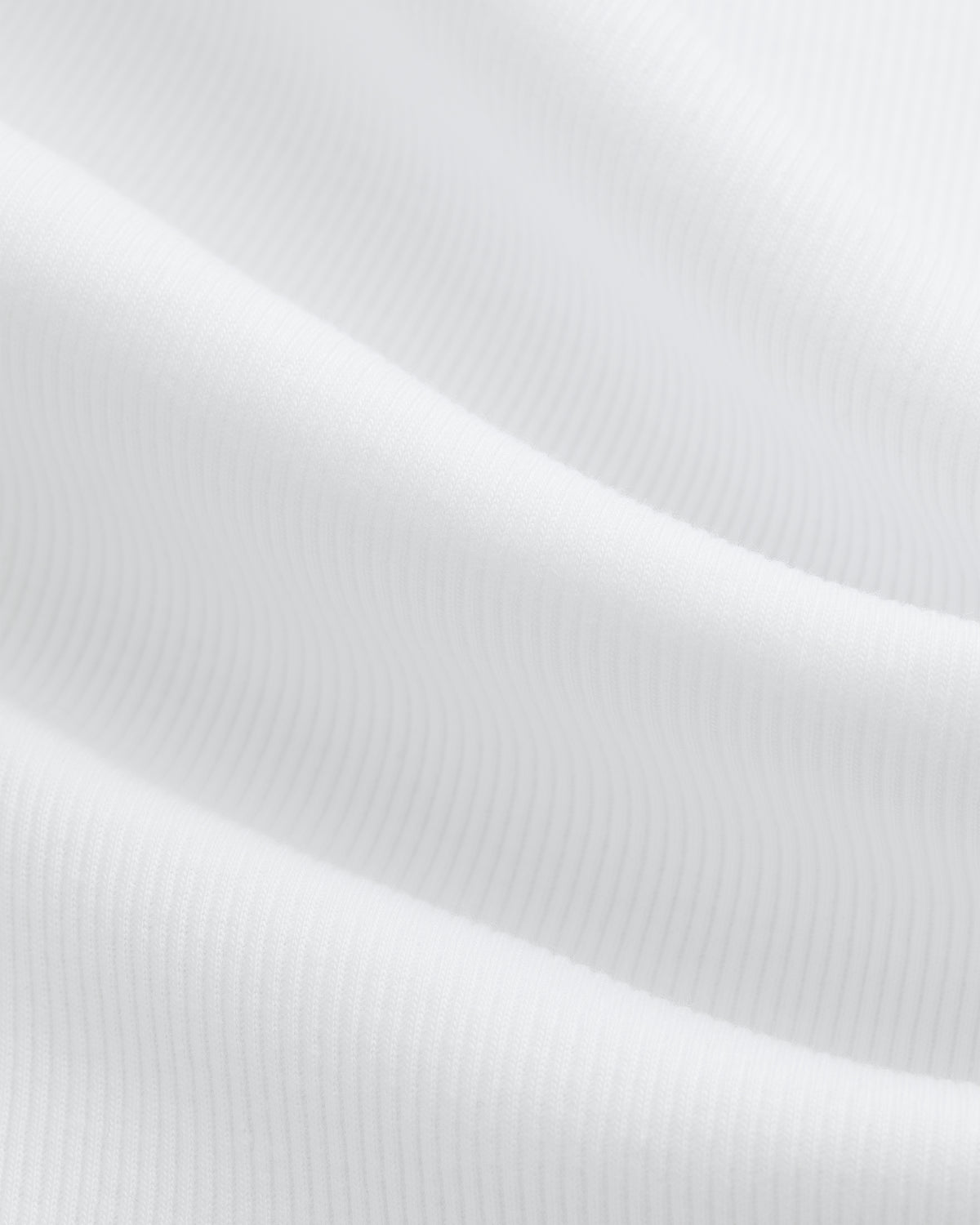 Close-up of ribbed white Tank Top 3-Pack fabric, showing soft wavy folds and a subtle textured pattern.