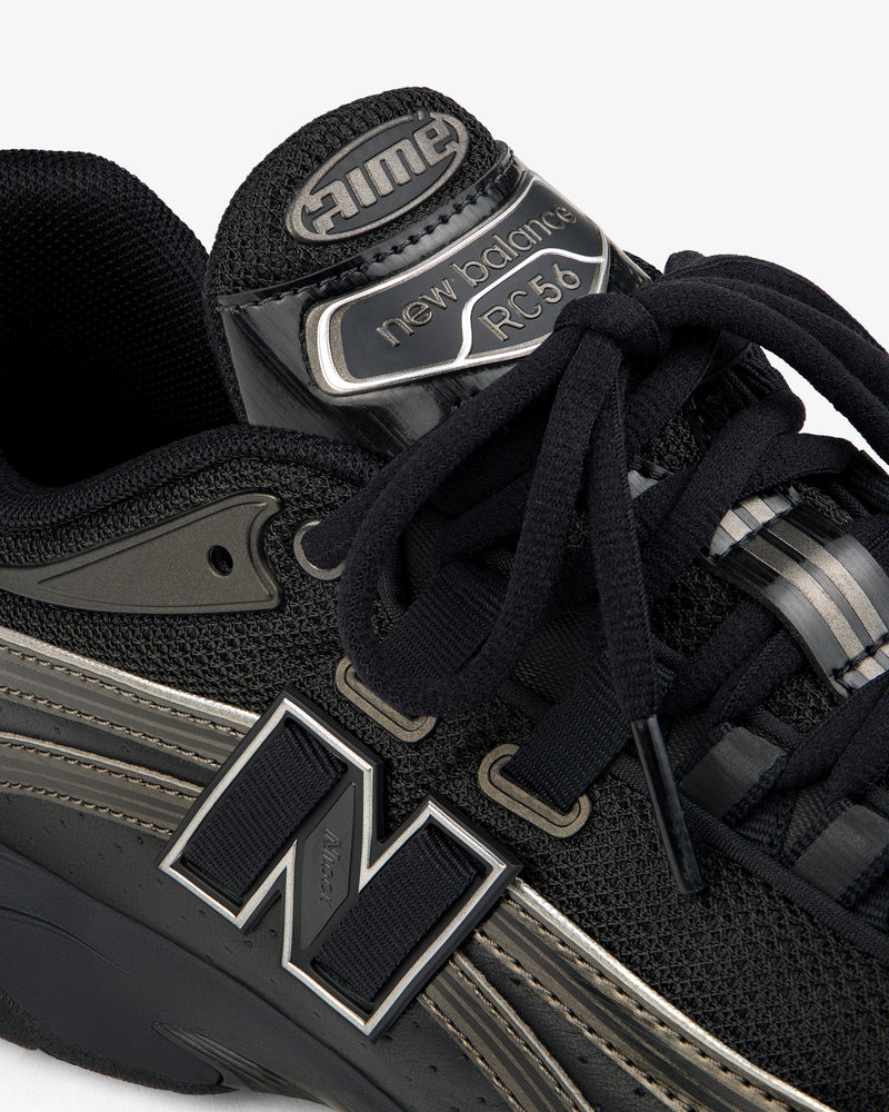 Close-up of a black ALD / New Balance RC56 sneaker with black laces and shiny silver detailing on tongue and sides.