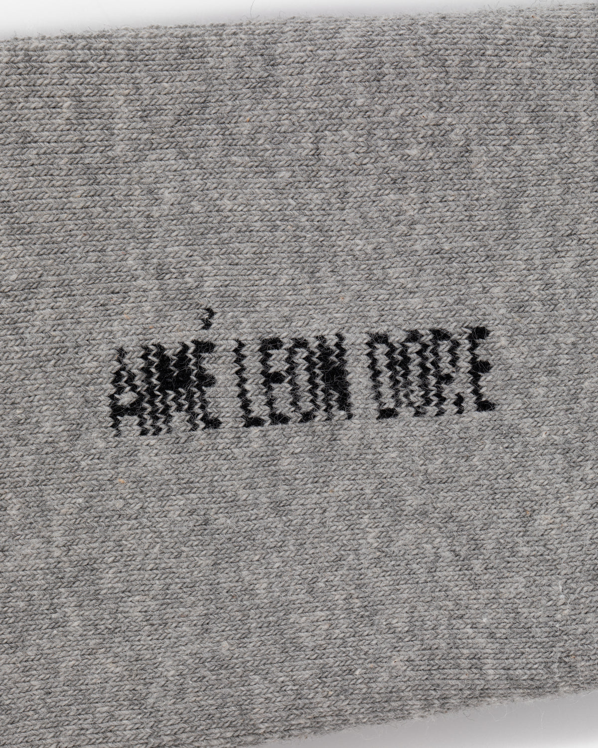 Close-up of gray Crew Sock 3-Pack with AIMÉ LEON DORE stitched in black, all-uppercase letters at the center.
