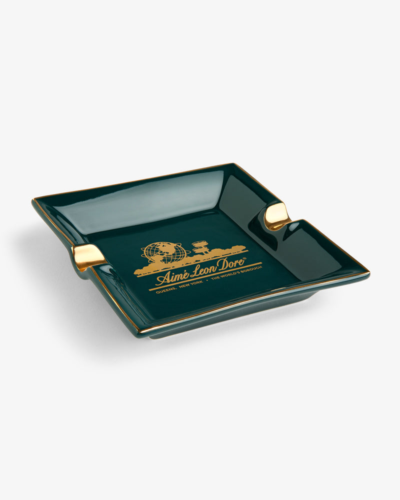 Unisphere Ashtray: dark green square with gold accents, Aimé Leon Dore logo and text in gold on the base.