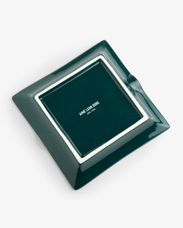 The Unisphere Ashtray is a square green ceramic piece with AIMÉ LEON DORE in white at the center.