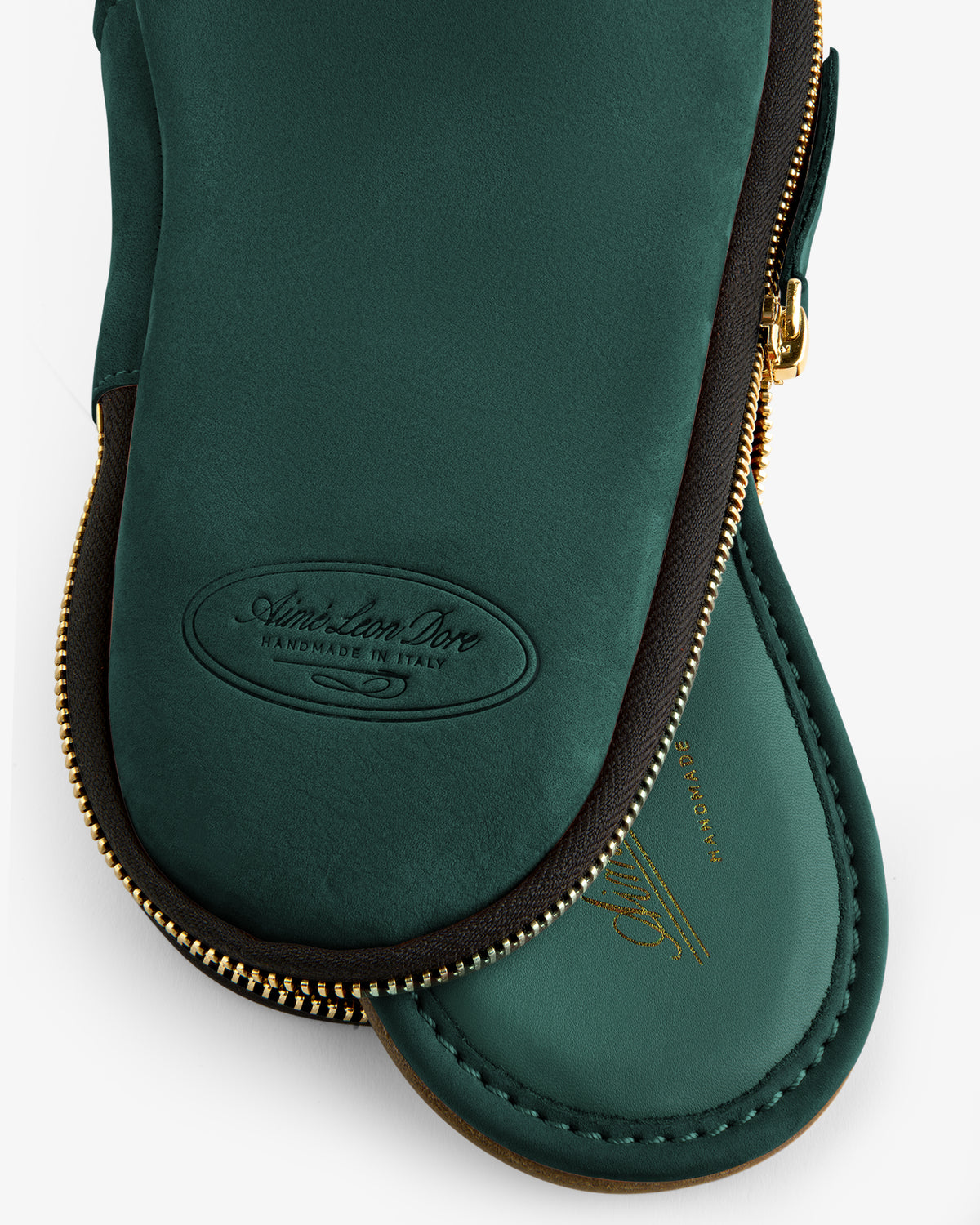 Close-up of green Nubuck Travel Slipper zip case with gold zipper and embossed "Handmade in Italy" text.