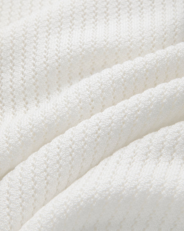 Close-up of Pointelle Knit Sweater’s white textured fabric, featuring soft ridges and a delicate knit in bright light.