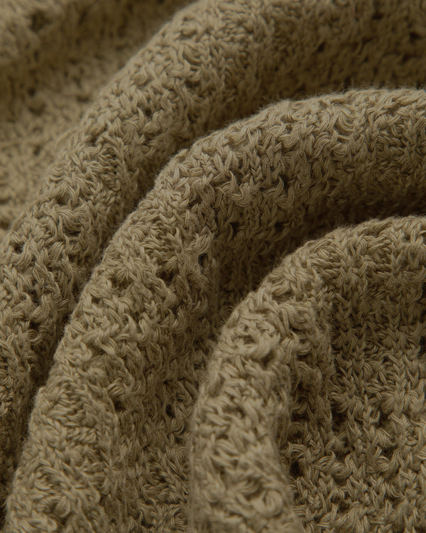 Close-up of textured, brown Checkered Crewneck Sweater with visible yarn and soft, wavy folds.