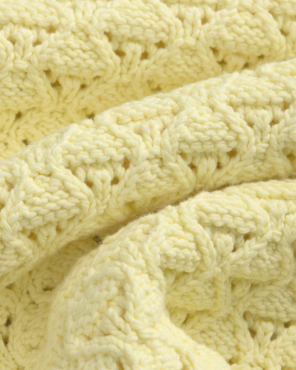 Close-up of the Eyelet Knit Crewneck Sweater in soft yellow, showing its textured, repeating eyelet pattern.