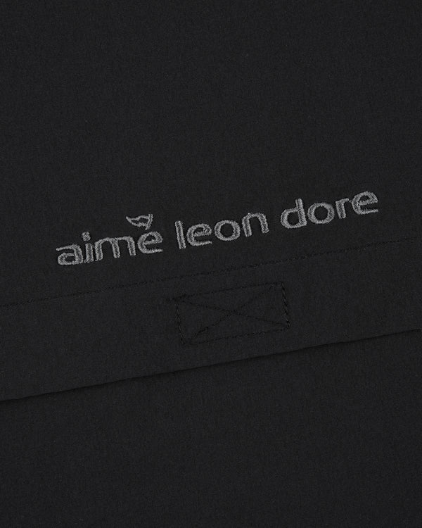 Detail of black ALD Golf Cordura Tips Jacket with aimé leon dore in gray lowercase embroidery.