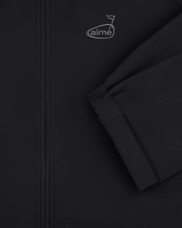 ALD Golf Cordura Tips Jacket close-up: zipper, folded sleeve, and small embroidered aime logo with flag above it.