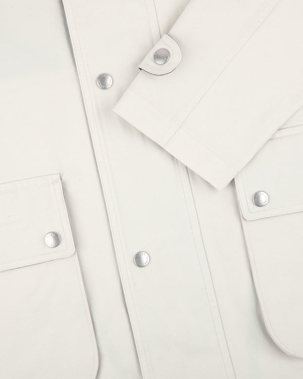 Close-up of a white Sailing Jacket with silver snaps and flap pockets, showing sleeve and front details.