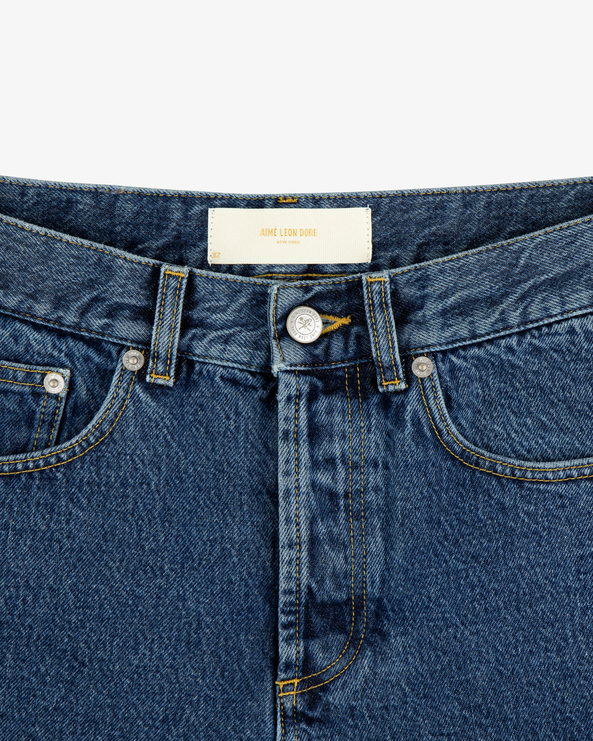 Close-up of ALD Straight Fit Denim in blue with waistband, belt loops, and a white "Aime Leon Dore" label.