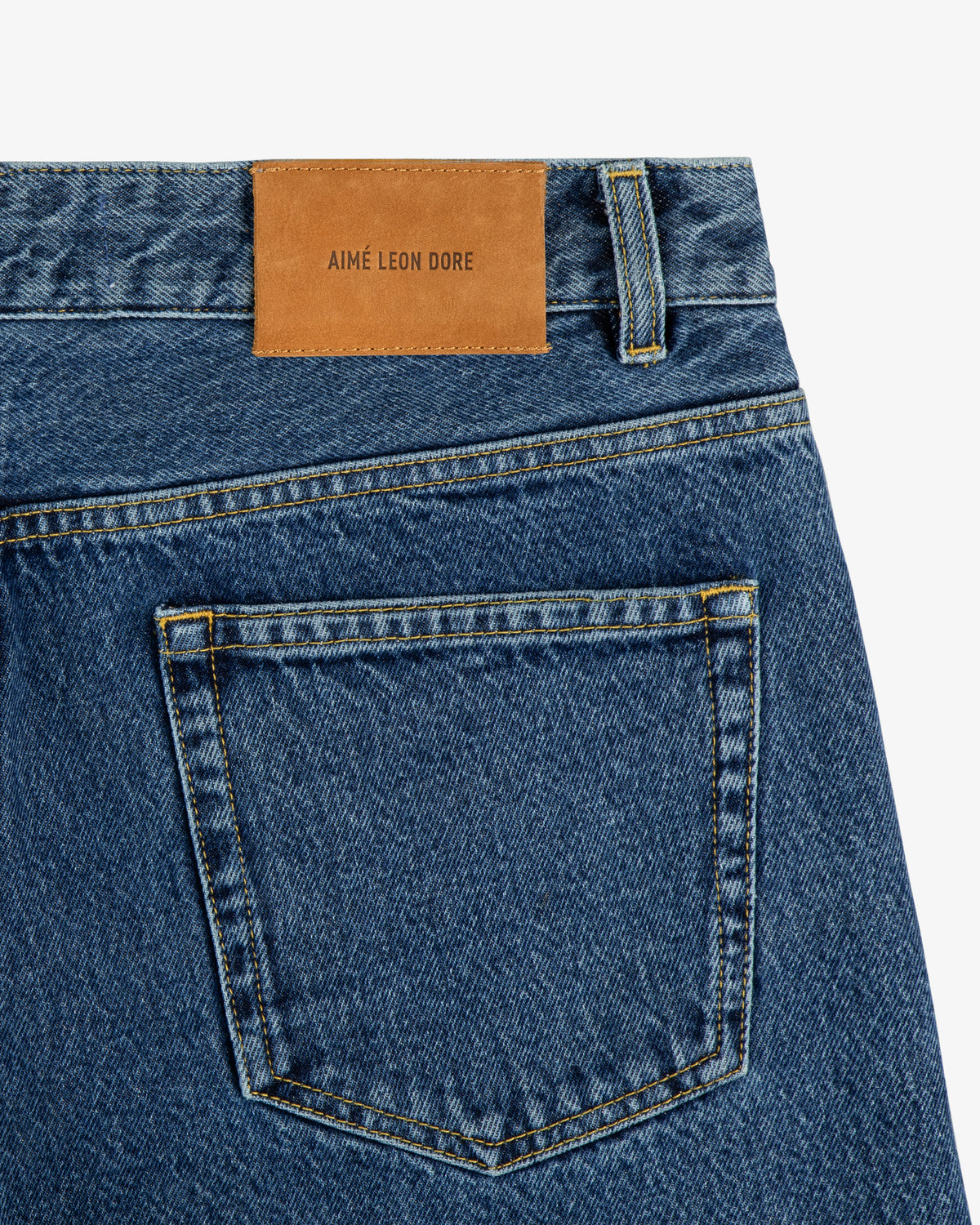 Close-up of ALD Straight Fit Denim in blue with a brown leather AIMÉ LEON DORE patch above the back pocket.