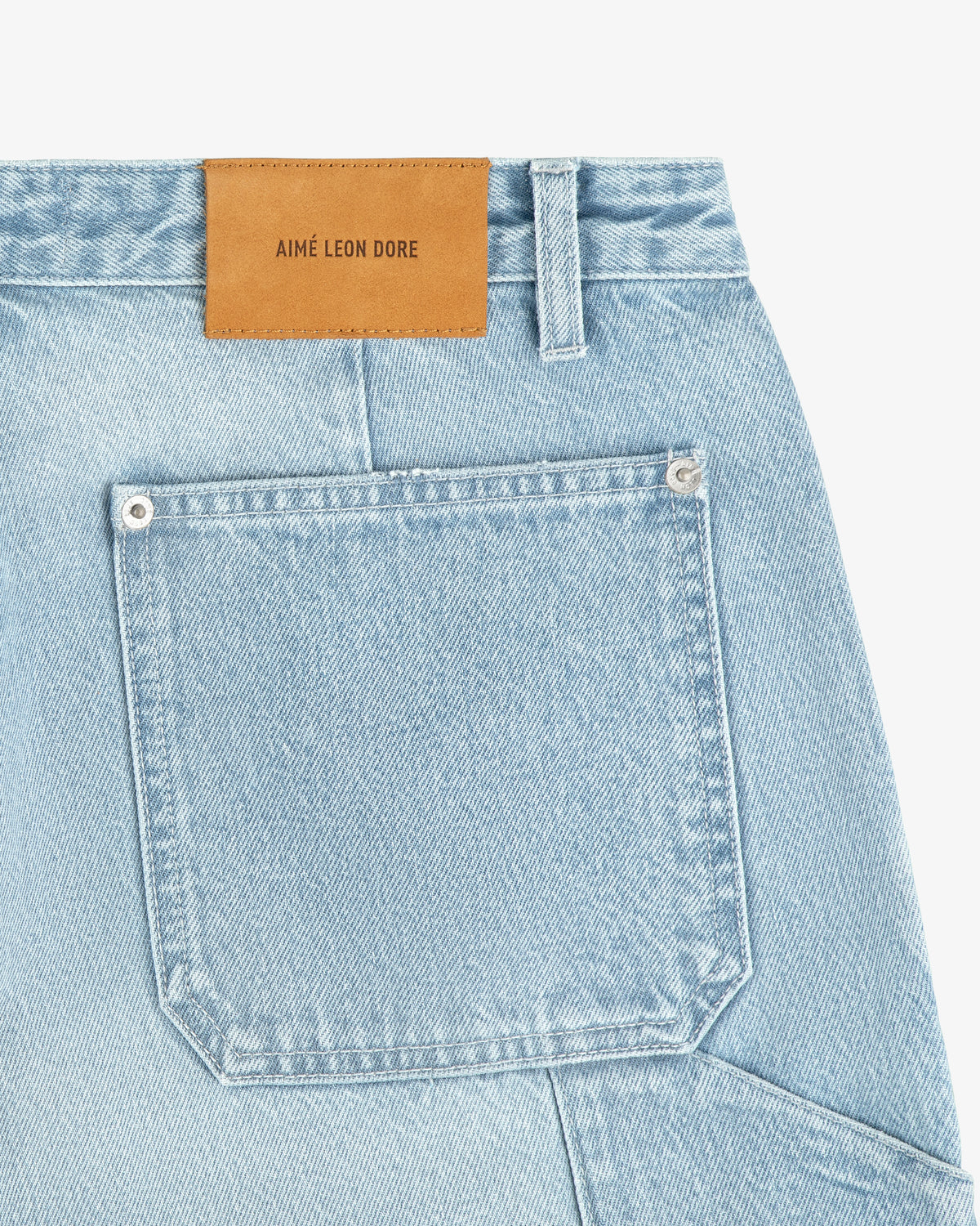 Close-up of light blue Denim Carpenter Pant with a large back pocket and brown Aimé Leon Dore leather patch on waistband.