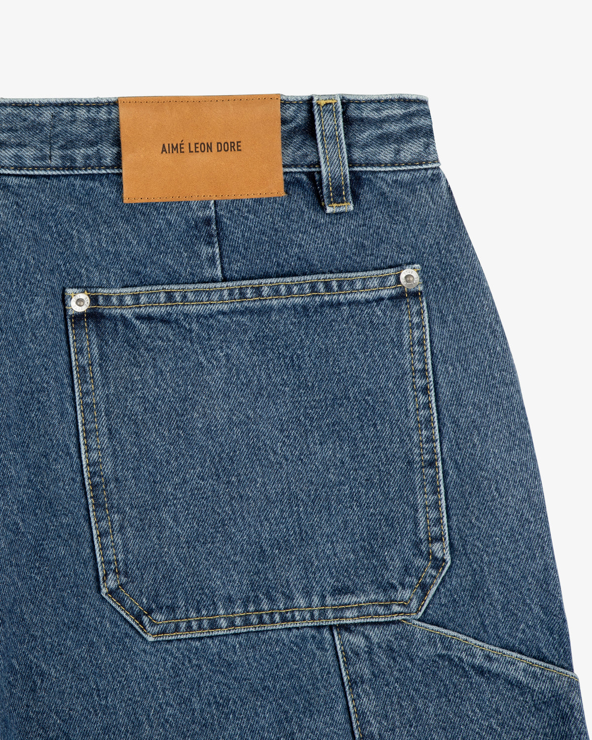 Close-up of Denim Carpenter Pant showcasing a large back pocket and a tan Aimé Leon Dore leather patch.