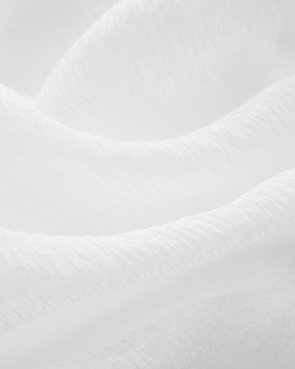 Close-up of Alpo Shirt’s soft, white fabric with gentle folds and subtle shadows for a calming, abstract look.