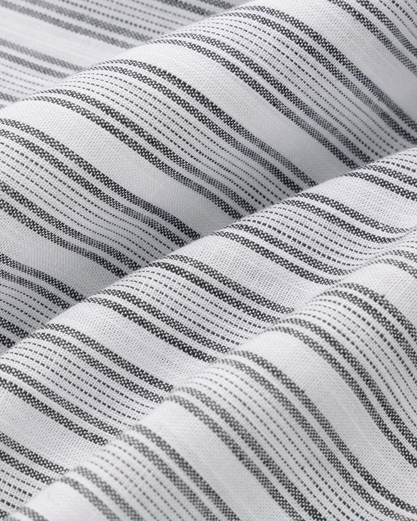 Close-up of Striped Leisure Shirt: white fabric with thin black diagonal stripes and a textured, woven look.