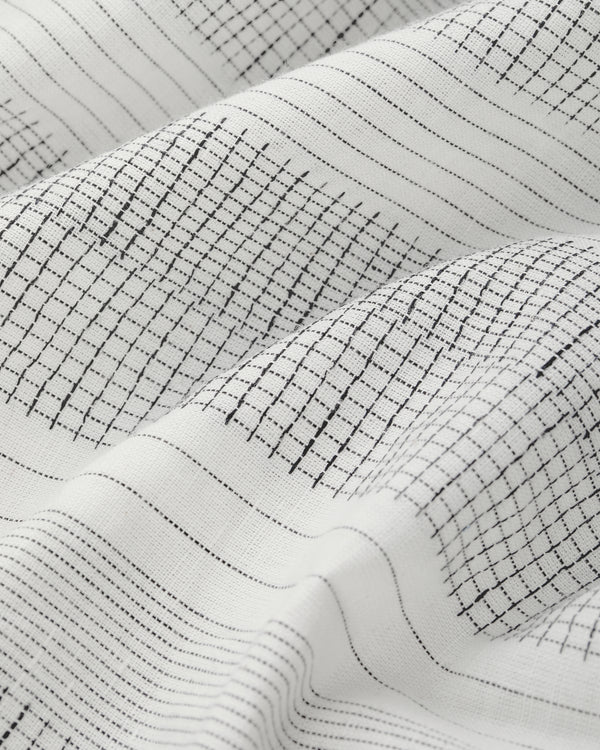 The Fil Coupé Leisure Shirt in white features thin black grid and stripe patterns, softly draped to show texture.