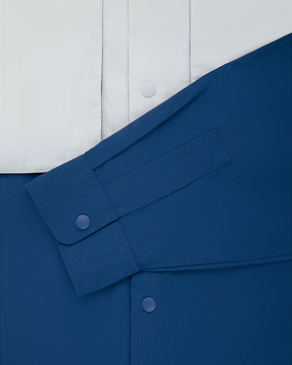 Close-up of the Colorblock Sport Shirt: white top, blue bottom, and blue sleeve with overlapping snap buttons.