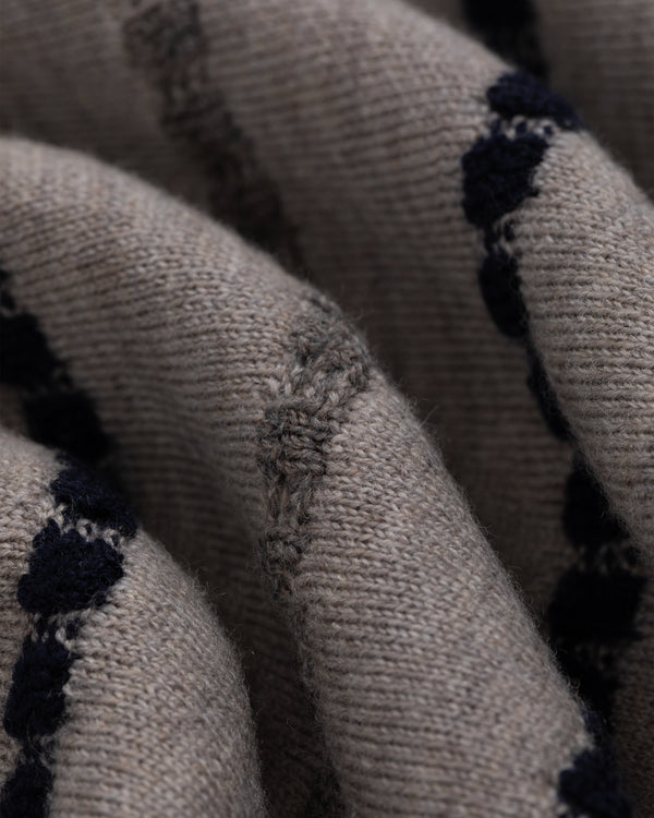 Close-up of Jacquard Stripe Polo Cardigan: beige knit with dark blue stripes and visible patch repair.