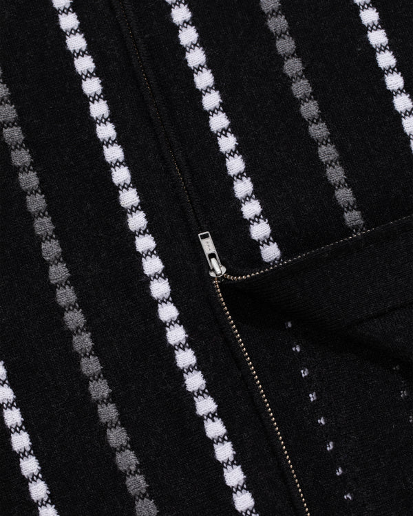 Close-up of Jacquard Stripe Polo Cardigan in black with white and gray stripes and a partially unzipped metal zipper.