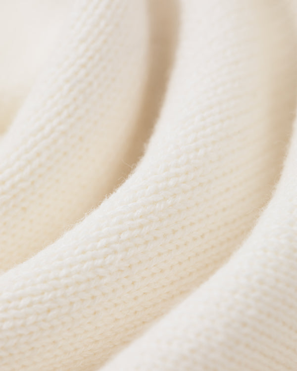 Close-up of the Heritage Mockneck Sweater’s soft, white ribbed knit fabric and gentle folds.