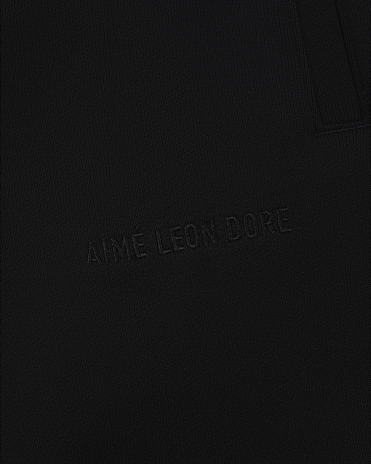 Close-up of black textured Tonal Logo Sweatpants with AIMÉ LEON DORE subtly embroidered in matching black thread.