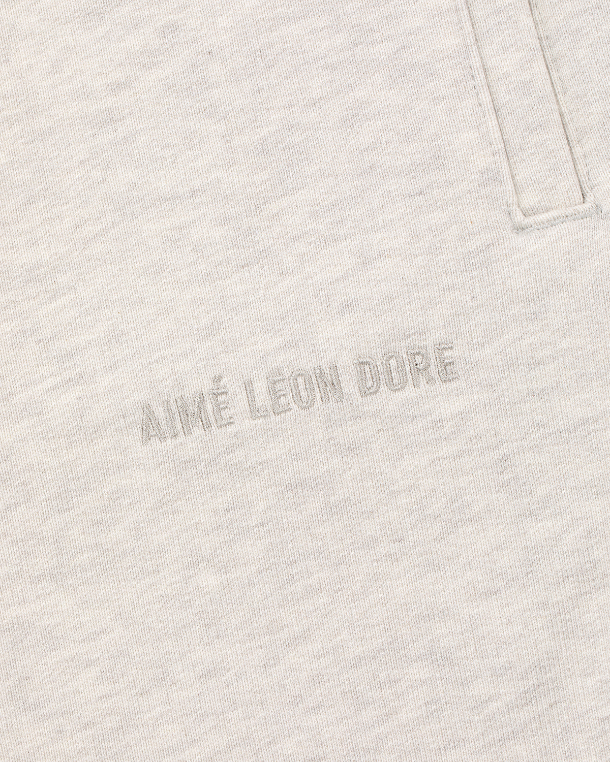 Close-up of light beige Tonal Logo Sweatpants with subtle AIMÉ LEON DORE embroidery below the pocket seam.