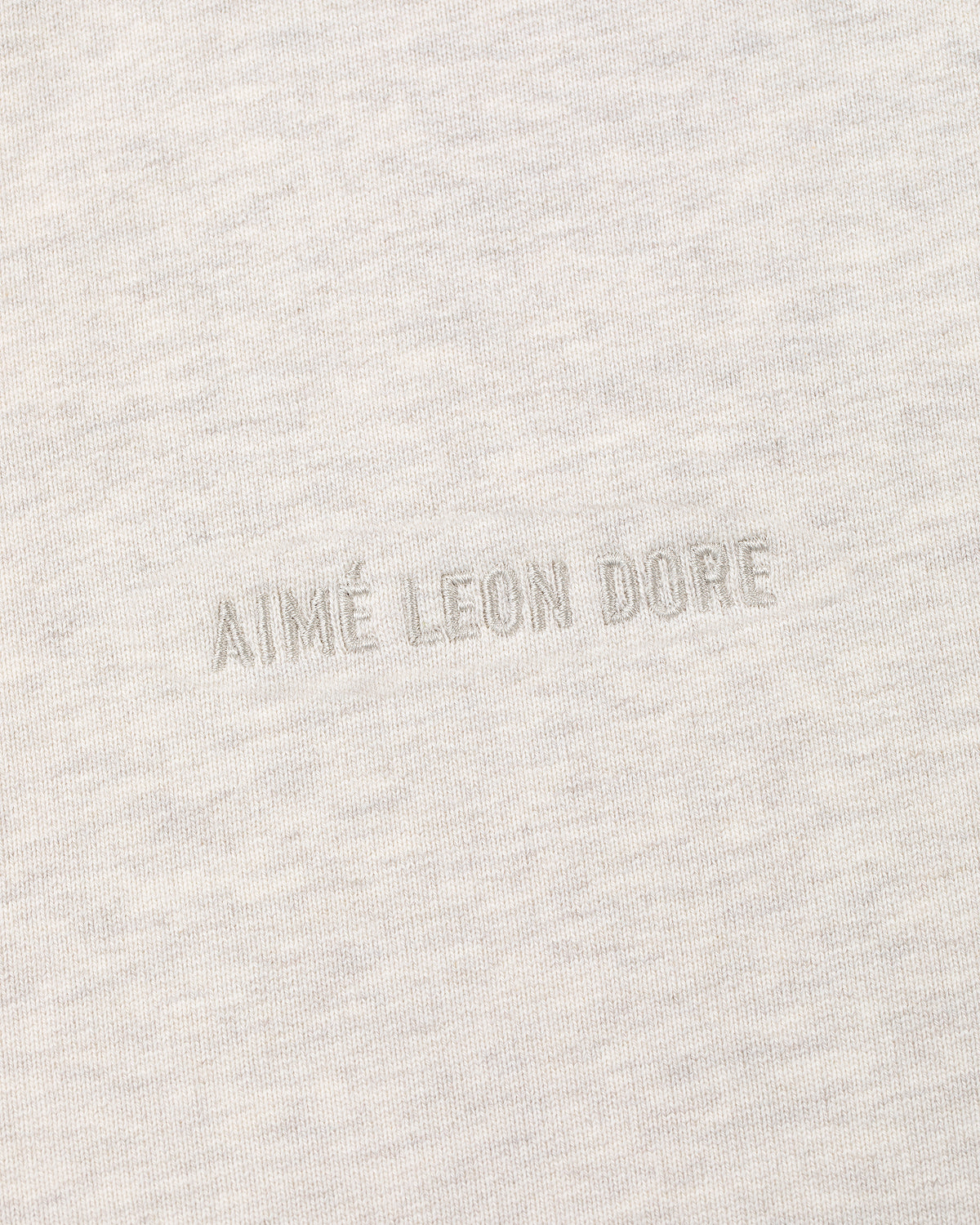 Close-up of light beige Tonal Logo Hoodie with AIMÉ LEON DORE subtly embroidered in matching thread at the center.