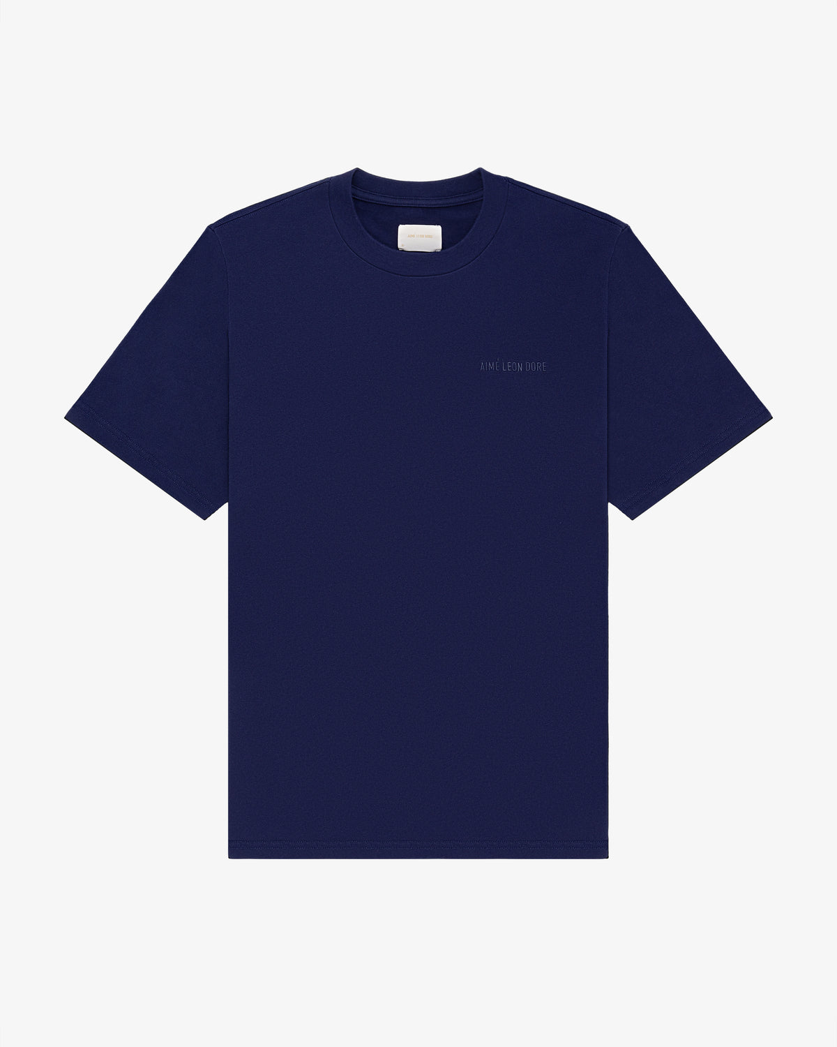 Tonal Logo Tee: navy blue short-sleeve shirt with a small white label and subtle left chest text.