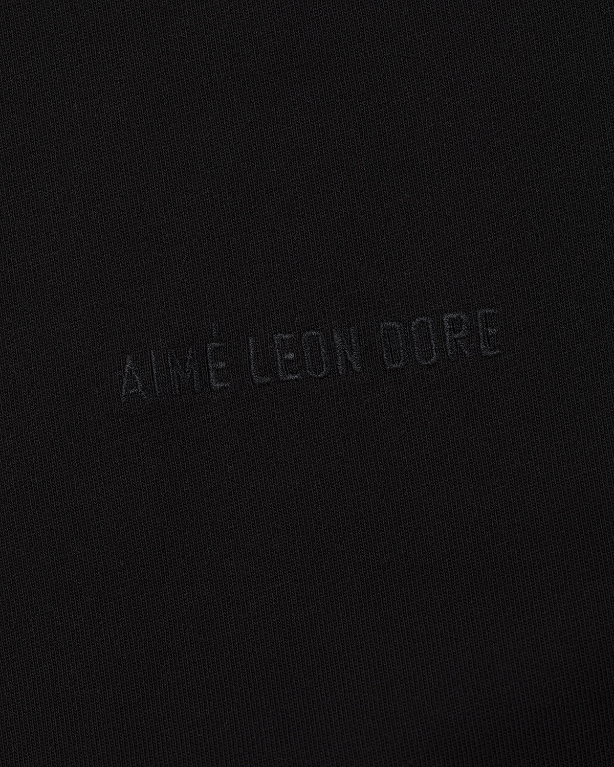 Long-Sleeve Tonal Logo Tee in black with AIMÉ LEON DORE subtly embossed in matching color at the center.