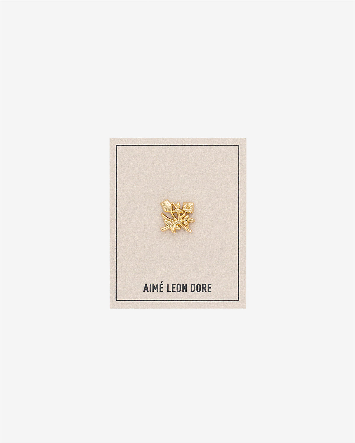 ALD Pin: Gold floral design with small gem, on cream AIMÉ LEON DORE card with thin black border.