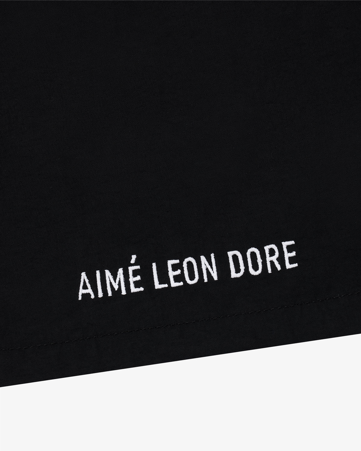Black Core Nylon Short with “AIMÉ LEON DORE” embroidered in white all-caps near the hem.