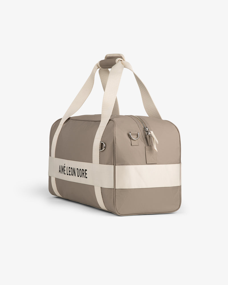 Nylon Duffle Bag in beige with white straps and AIMÉ LEON DORE logo, displayed on a plain white background.