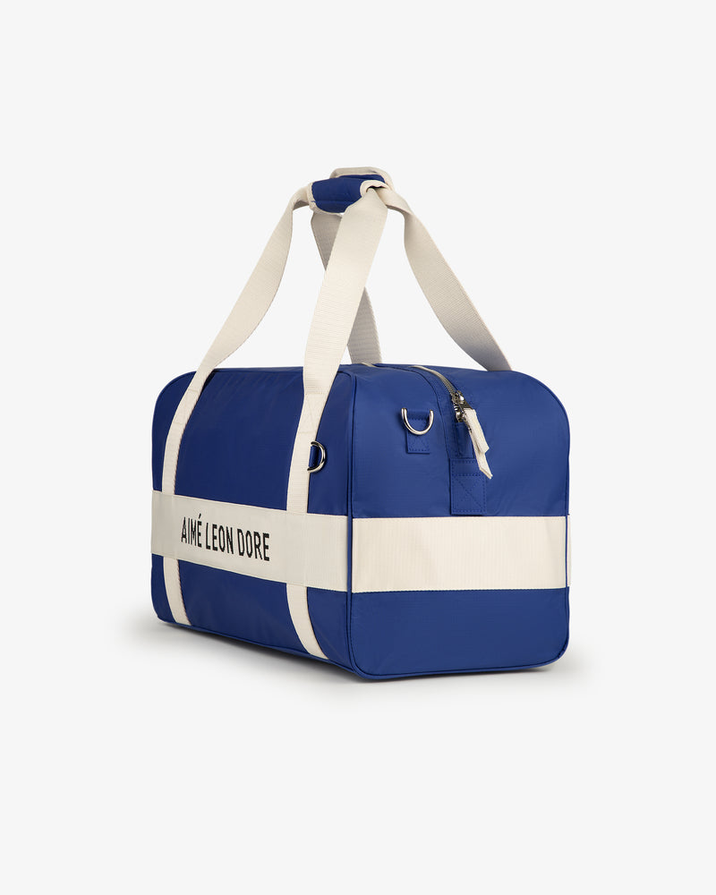Nylon Duffle Bag in blue with white straps, stripe, and Aimé Leon Dore text on the side.