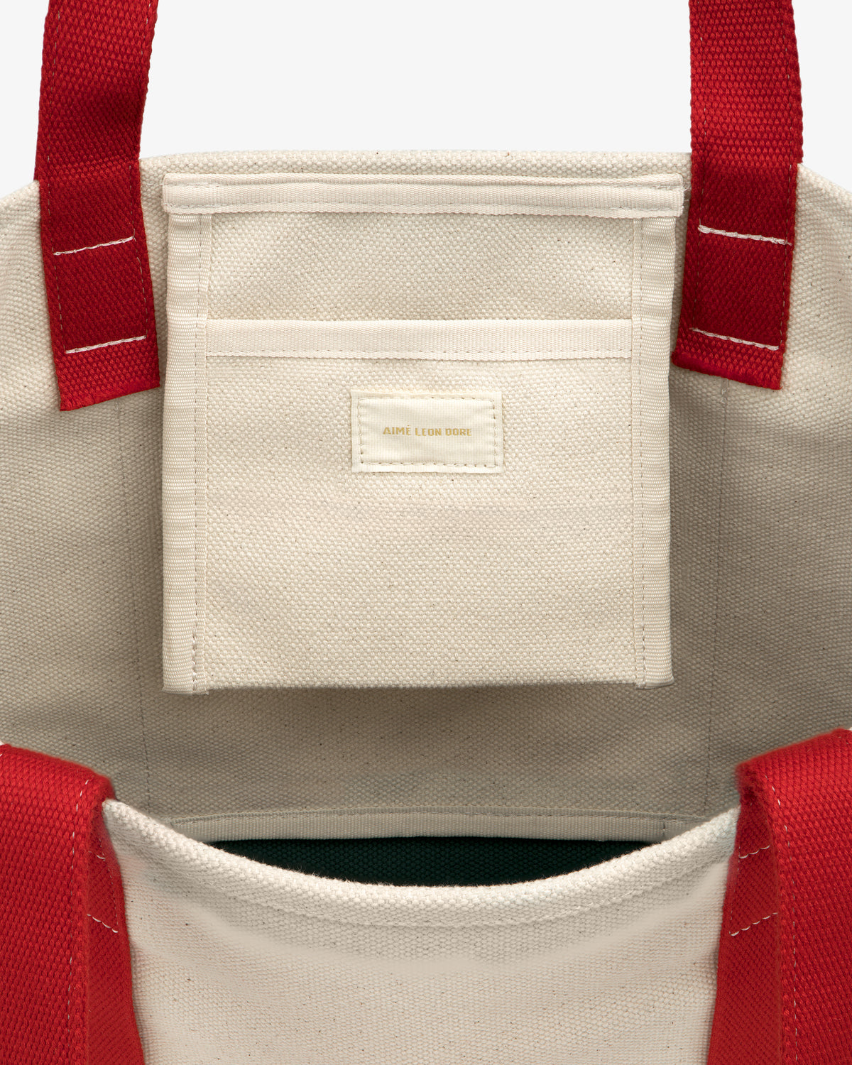 Large Crest Contrast Tote Bag with red handles, an interior pocket, and a small beige label on the pocket.