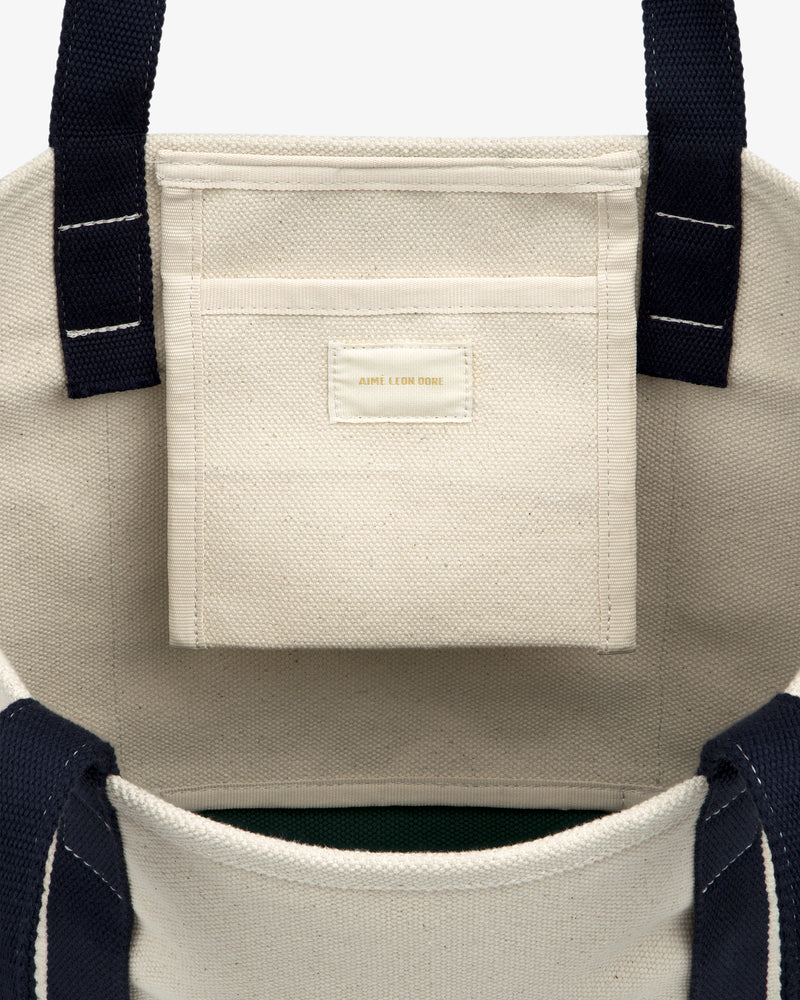 Small Crest Contrast Tote Bag features navy handles and a small interior pocket, shown from a top view.