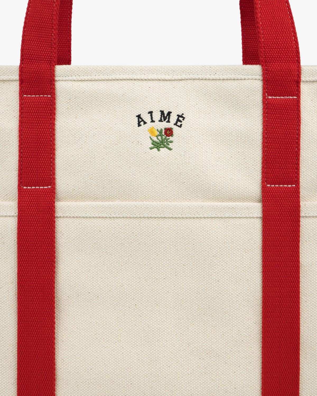 Large Crest Contrast Tote Bag: cream canvas with bold red straps, AIMÉ text, and a small embroidered flower on front.