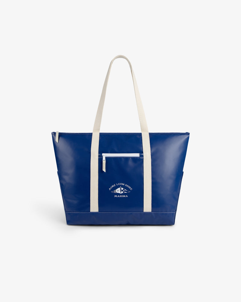 Carryall Marina Tote—blue with white straps, front pocket, and white graphic text on the front.