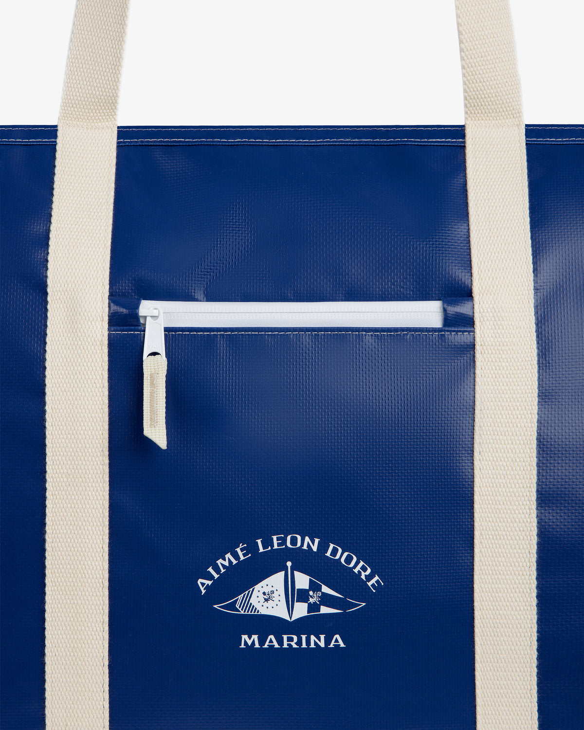Carryall Marina Tote: blue bag with cream handles, front zipper pocket, and Aimé Leon Dore flag logo.