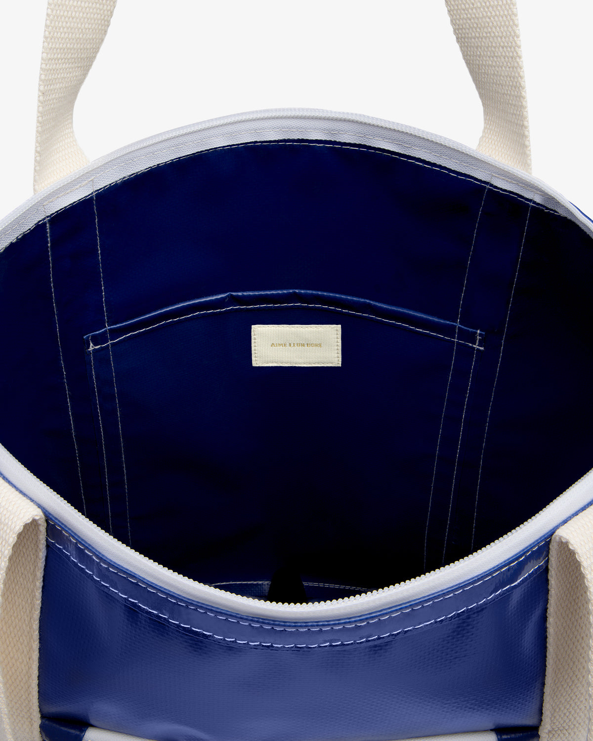 Carryall Marina Tote with cream handles, open to reveal navy lining and a small interior pocket with label.