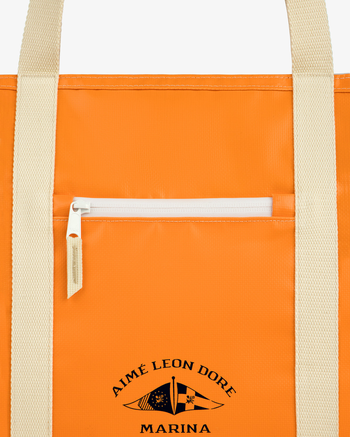 Close-up of the Carryall Marina Tote, an orange bag with beige handles, white zip pocket, and Aimé Leon Dore Marina text.