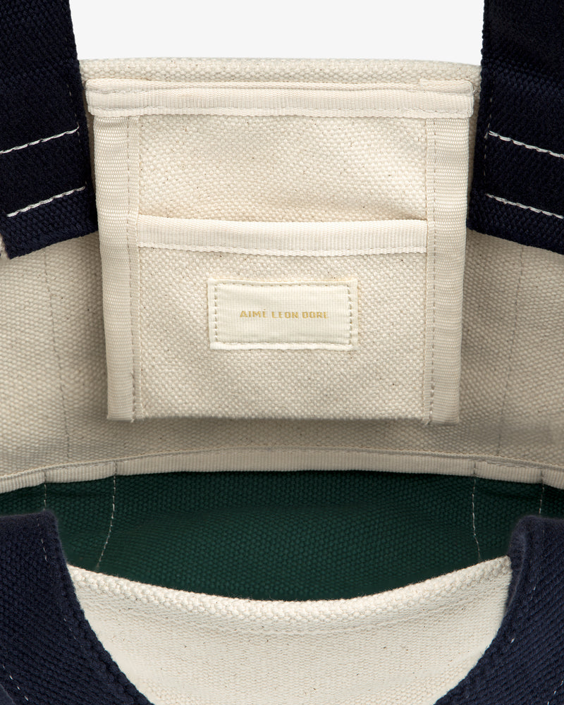 Close-up of the Mini Crest Contrast Tote Bag’s interior pocket with Aime Leon Dore label on cream fabric.