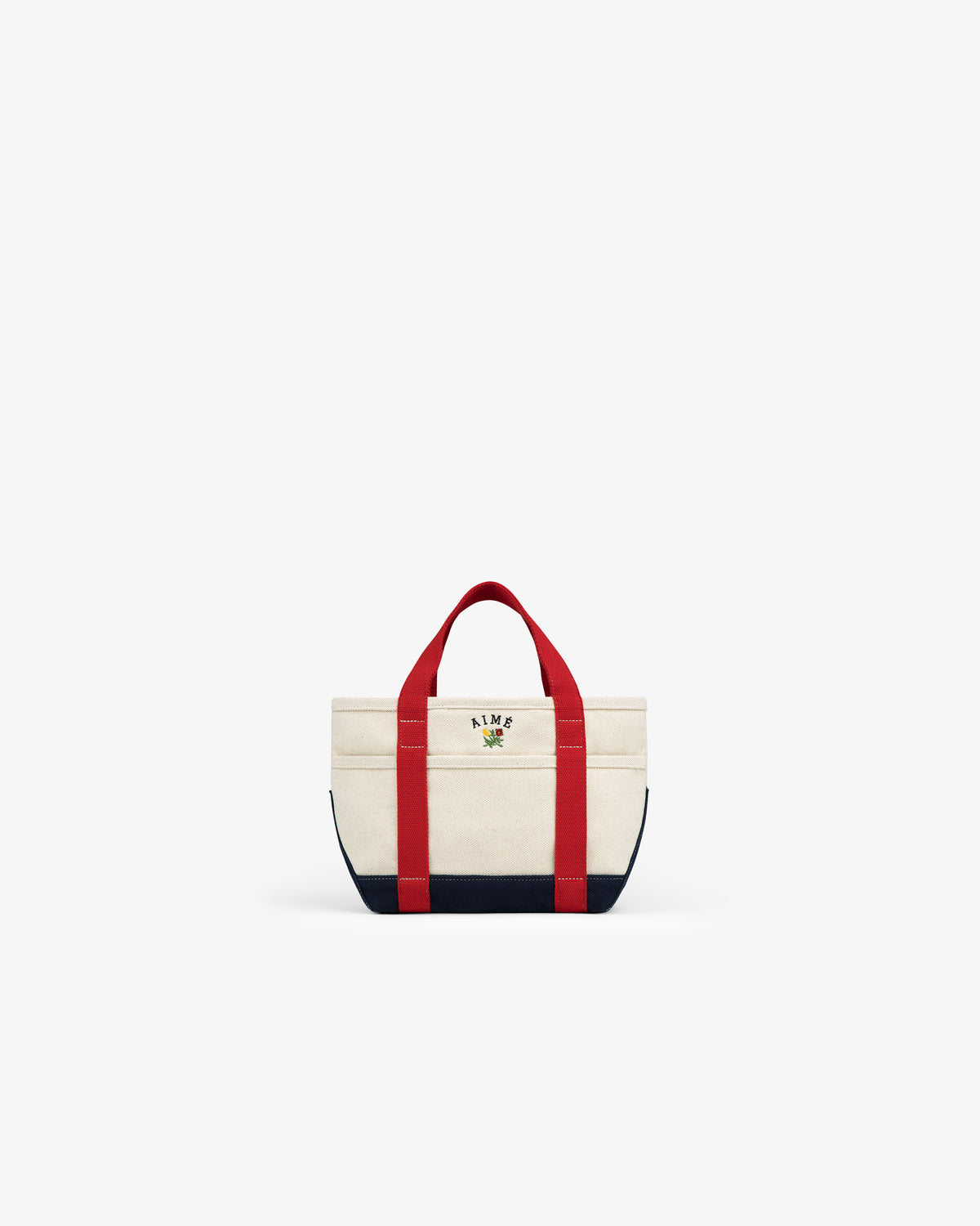 The Mini Crest Contrast Tote Bag is cream with red handles, navy accents, and KIME text plus a small flower on the front.