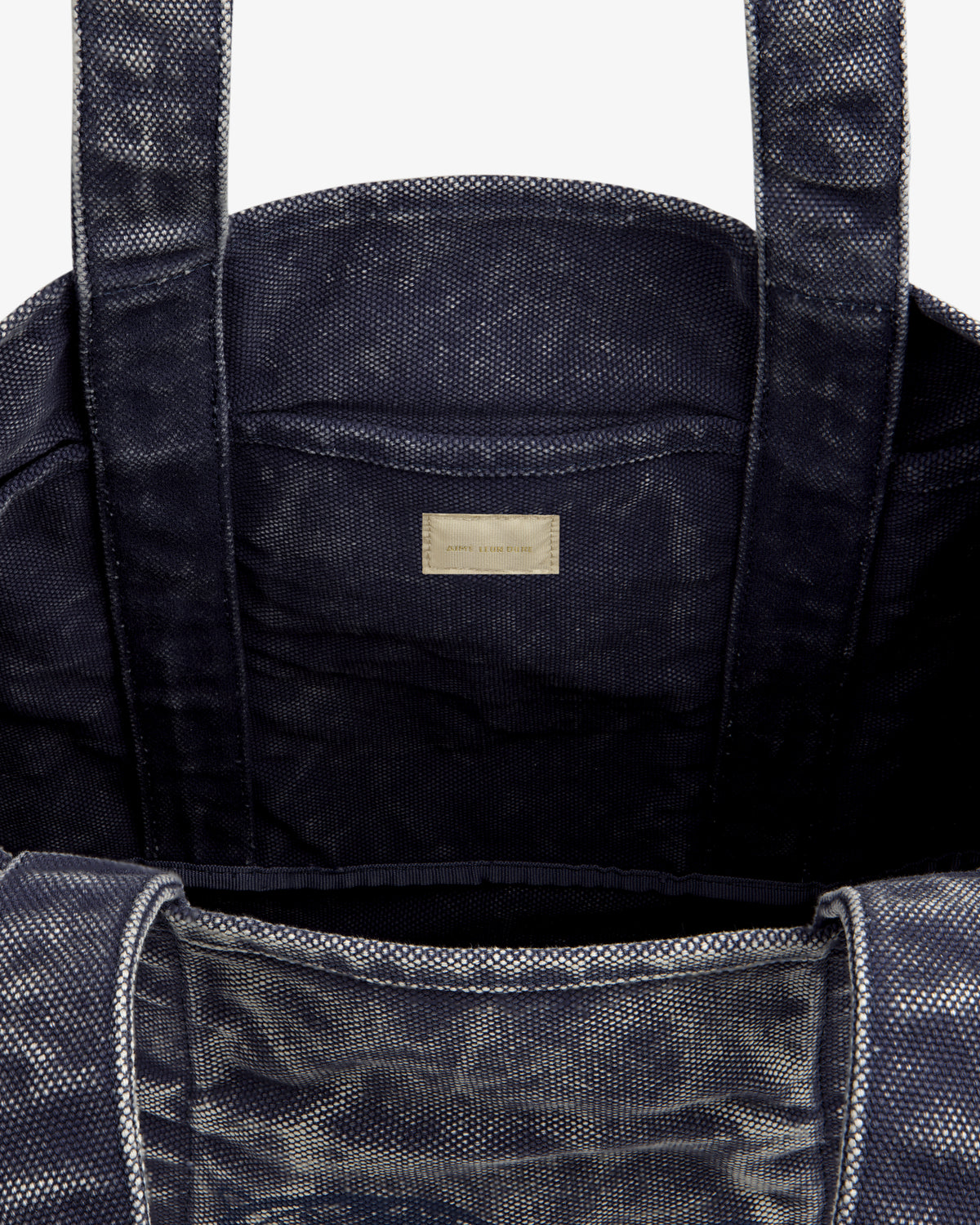 Close-up of the Sun Faded Large Unisphere Tote Bag's dark textured interior with two handles and a labeled inner pocket.