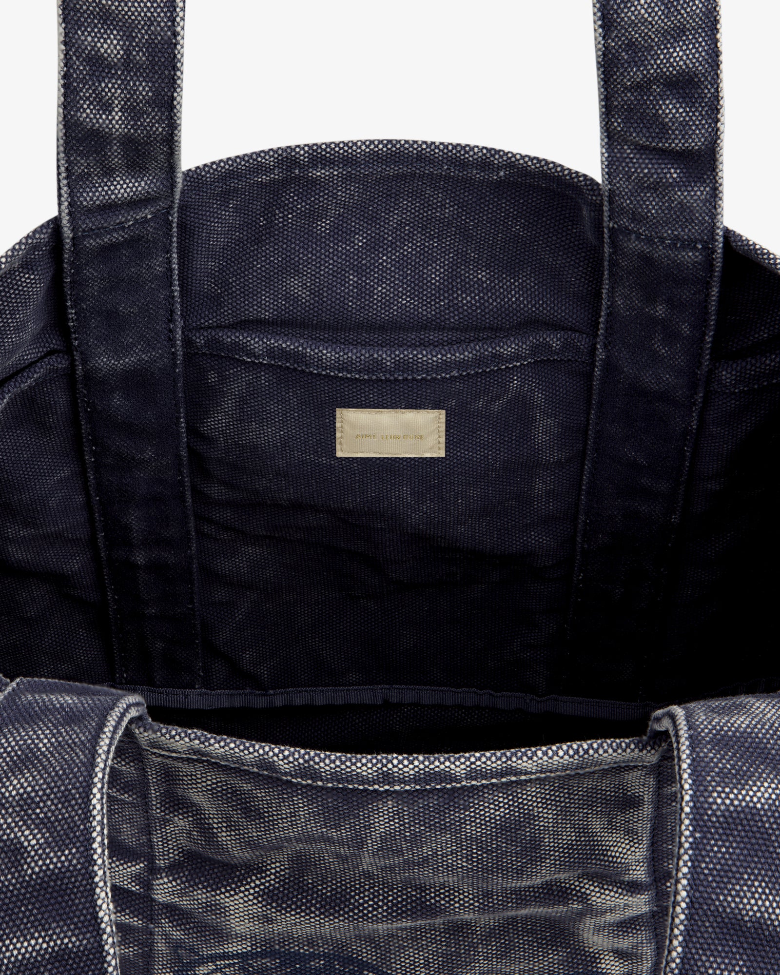 Close-up of the Sun Faded Large Unisphere Tote Bag's dark textured interior with two handles and a labeled inner pocket.