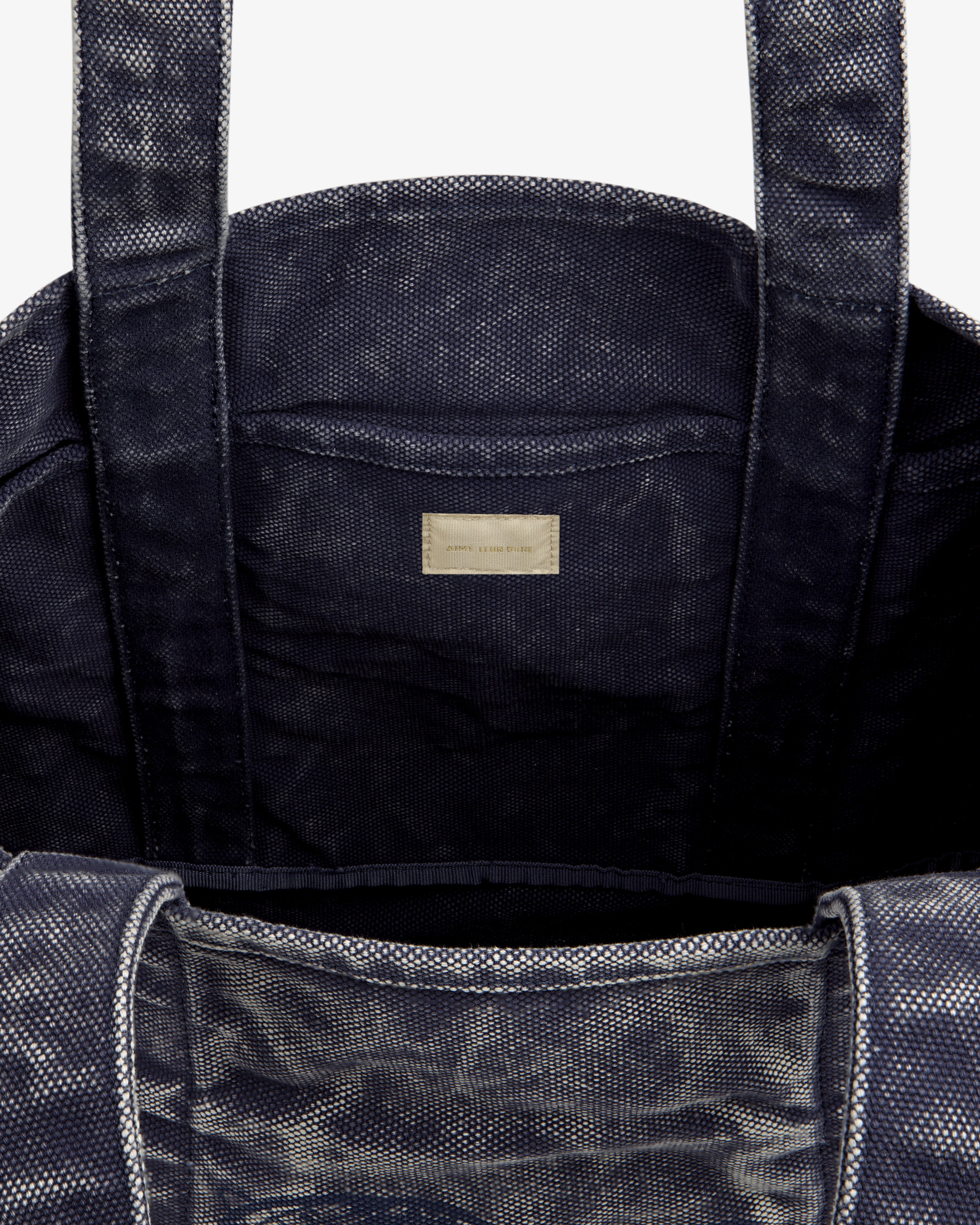 Close-up of the Sun Faded Large Unisphere Tote Bag's dark textured interior with two handles and a labeled inner pocket.