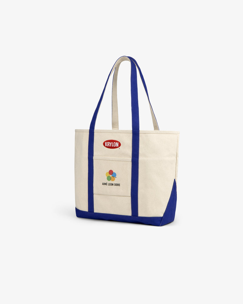 Krylon Tote Bag in beige with blue straps and trim, featuring Krylon and Aimé Leon Dore logos on the front.
