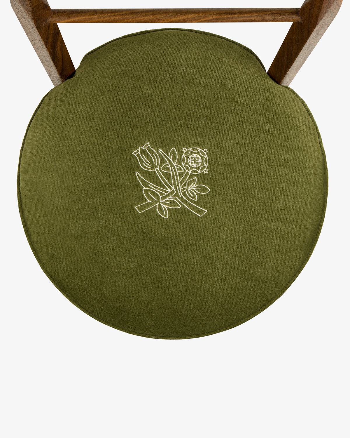Round olive green cushion with white floral embroidery on a Queens Crest Valet Chair, viewed from above.