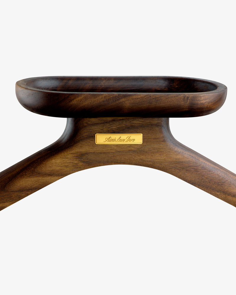 Close-up of the Queens Crest Valet Chair’s dark wooden hanger with a gold nameplate on a white background.