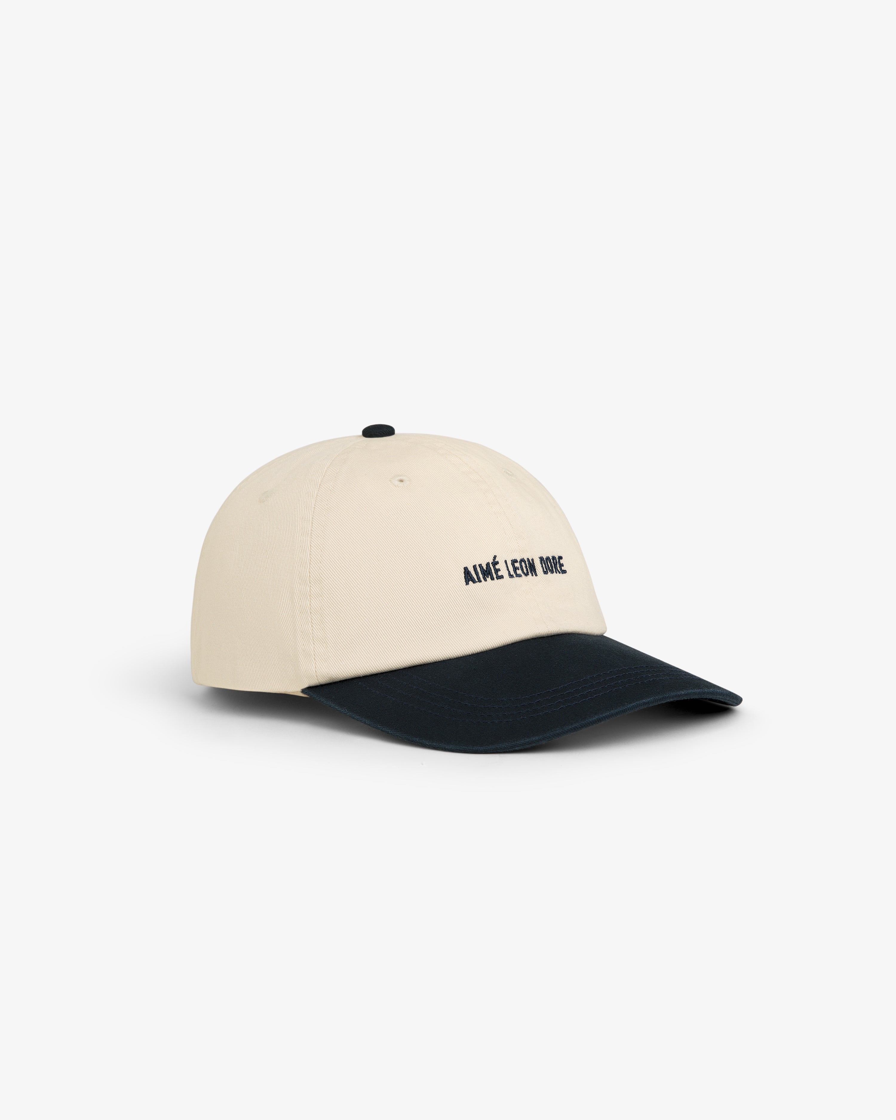 Washed Chino Hat in beige with a black curved brim and AIMÉ LEON DORE embroidered in black on the front.
