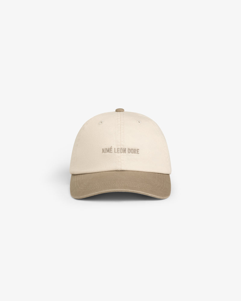 Washed Chino Hat in beige with brown brim and AIMÉ LEON DORE embroidered on front, shown on white background.