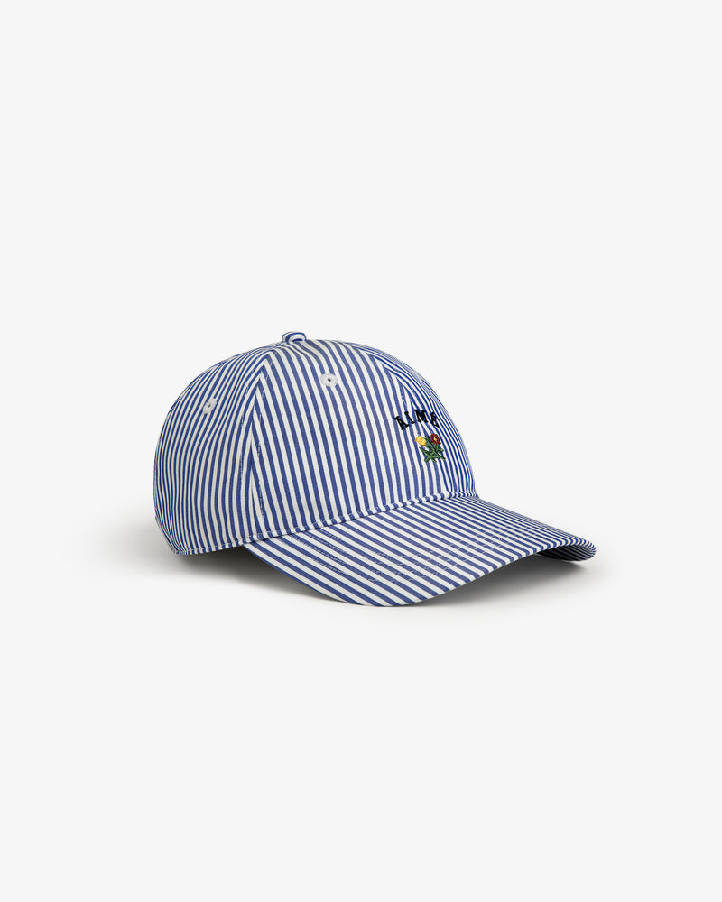 Striped Crest Logo Hat in blue and white with small front embroidery, shown on a white background.